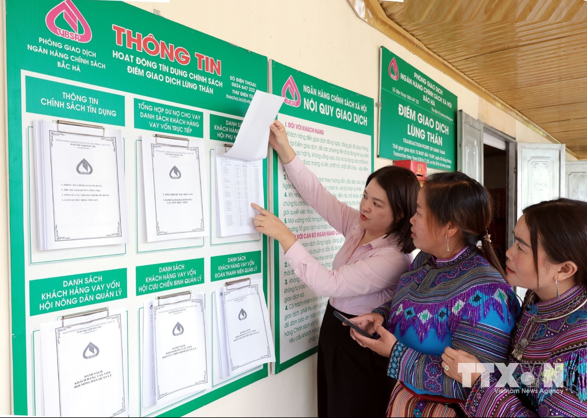 Đối chiếu danh sách hộ vay trên điện thoại với danh sách niêm yết công khai tại điểm giao dịch xã Lùng Thần, Lào Cai. (Ảnh: Trần Việt/TTXVN)